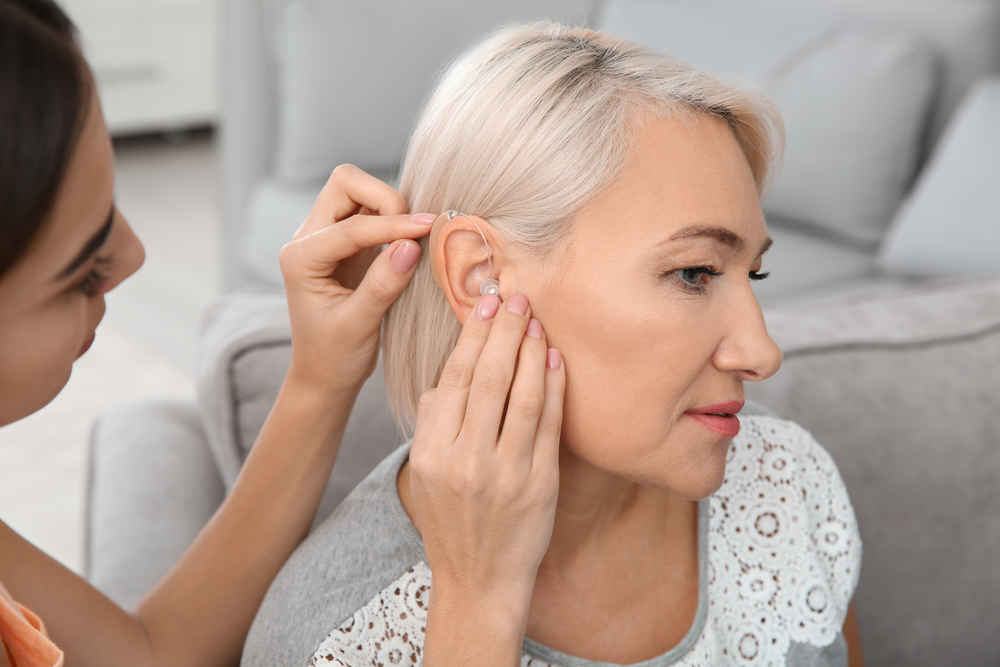 Audiologist fixing hearing aid