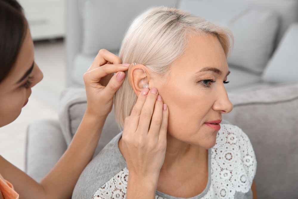 Audiologist fixing hearing aid on patient