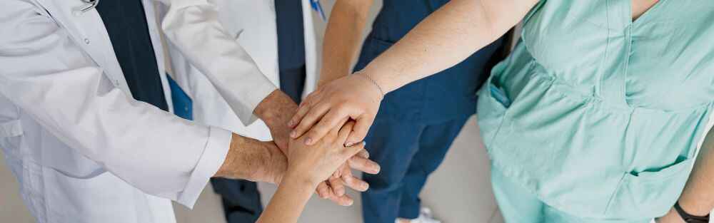 Team of ENT specialists & audiologists putting their hands together to represent teamwork